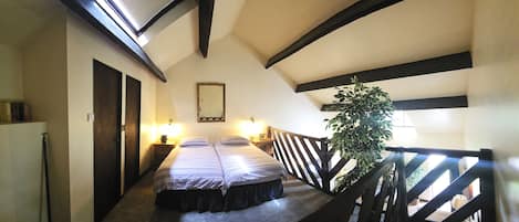 A room with a bed, a nightstand, a mirror, and a potted plant.