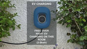 Une borne de recharge pour véhicules électriques avec un panneau indiquant que la recharge est gratuite pendant la nuit, pour une capacité de 3 à 5 kWh.