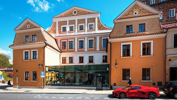 A building with a glass entrance and a red sports car parked in front. - Fontana Boutique (Lublin)
