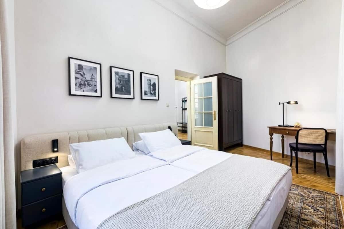 Une chambre bien rangée, avec un grand lit, des tables de chevet, un bureau et une armoire.