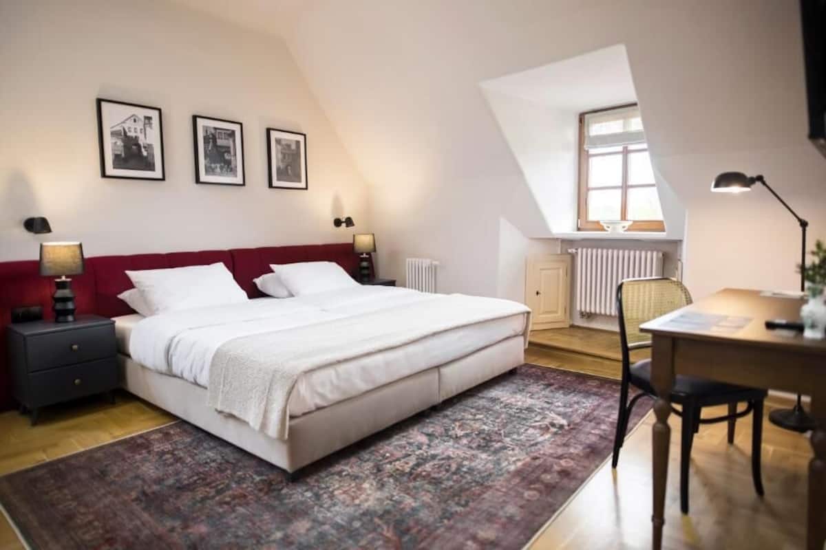 Une chambre avec un lit, un bureau et une chaise. Il y a trois tableaux encadrés accrochés au mur.