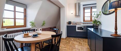 A modern kitchen with a round wooden table, black chairs, and a herringbone wood floor.
