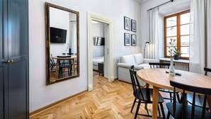 A modern living room with a wooden herringbone floor, a round dining table, and a large mirror. - Fontana Boutique (Lublin)