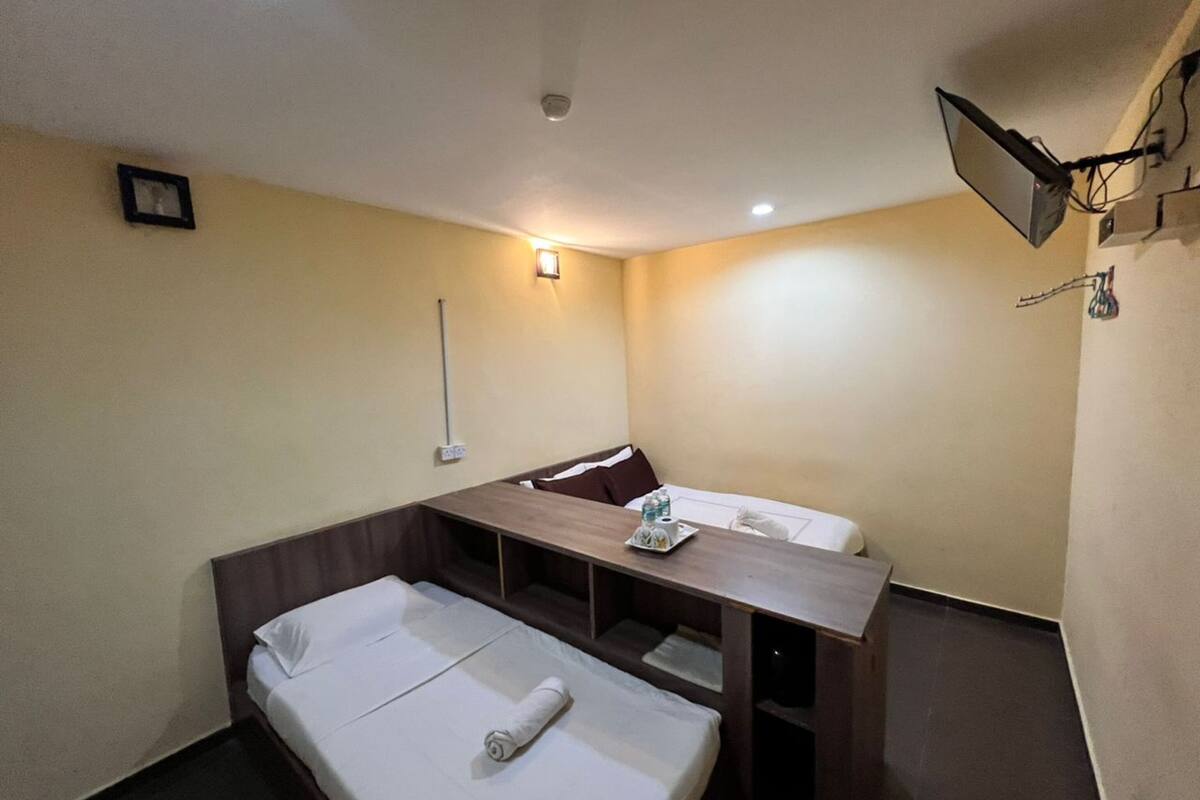 A small, compact hotel room with a single bed, a desk, and a chair.