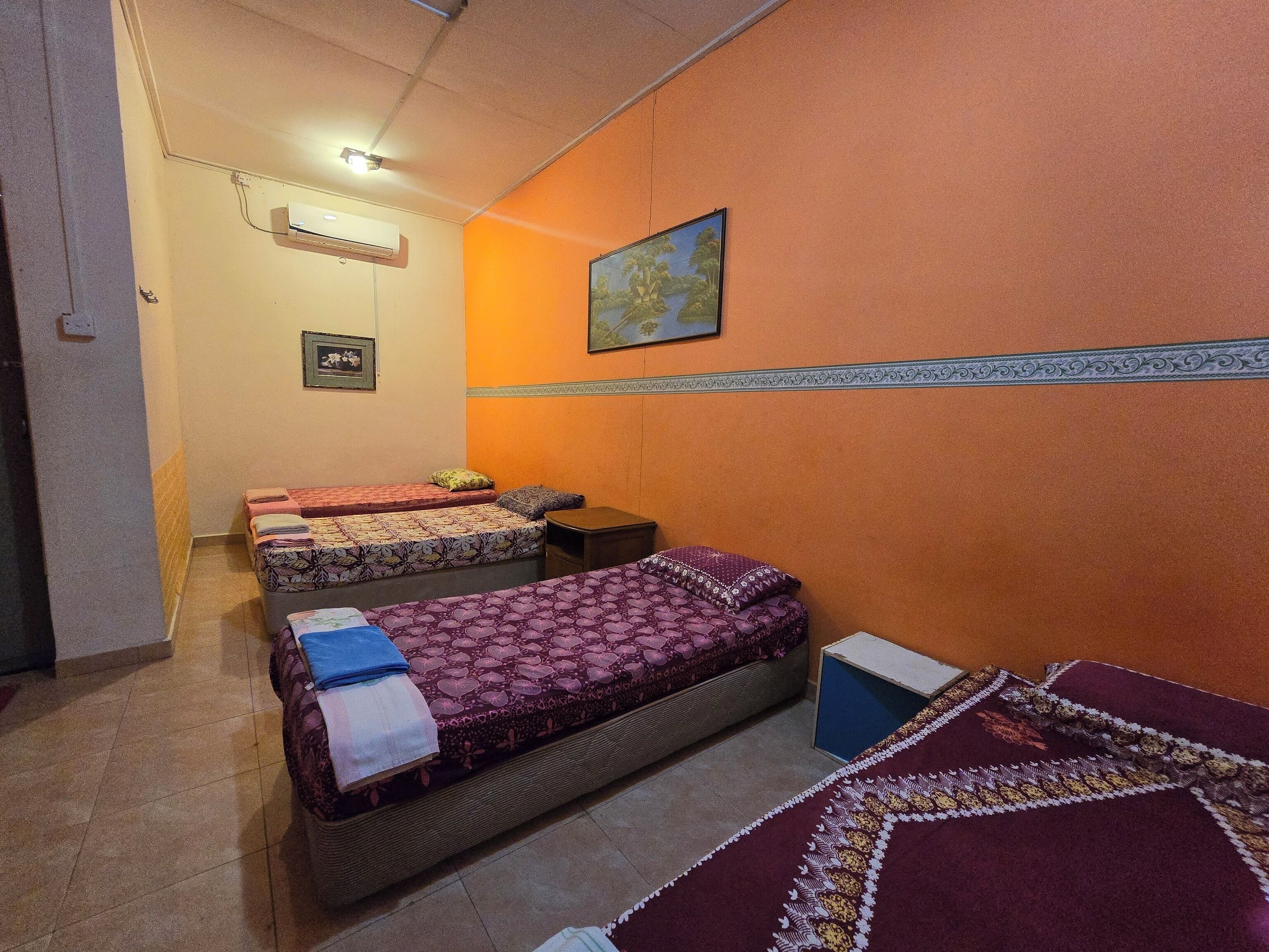 A room with two beds, a small table, and a wall-mounted air conditioner.