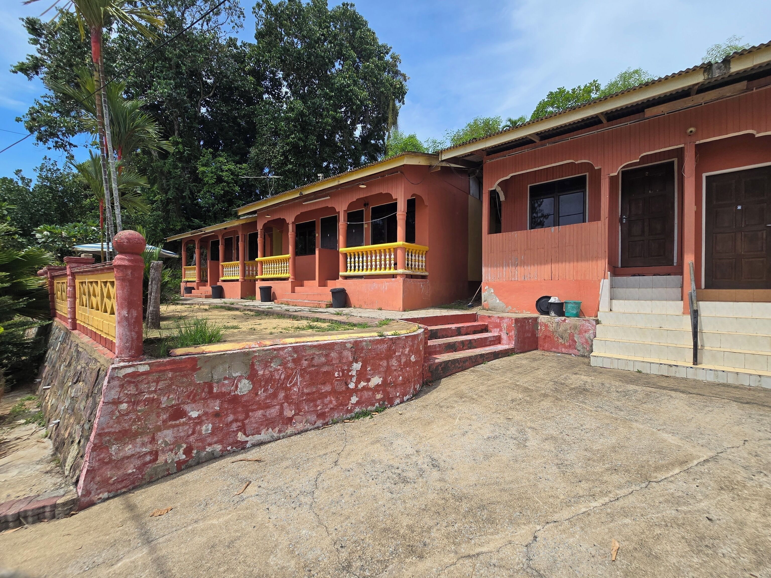 A building with a red facade, multiple balconies, and a concrete entrance area.