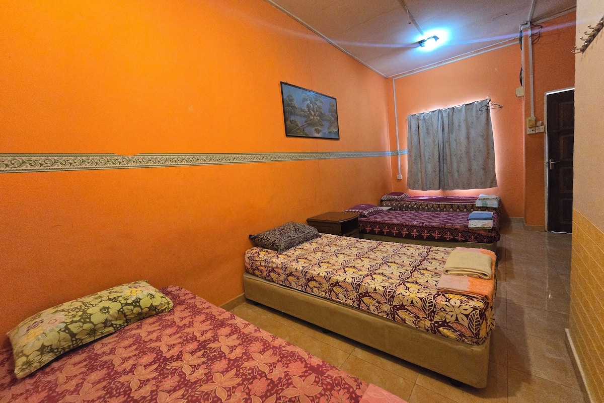 A room with two beds, a small table, and a painting on the wall.