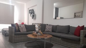 A modern living room with a grey sectional sofa, a round coffee table, and a small side table. - Loft in Dbayeh,including Generator, Prime Location (Dbayeh)