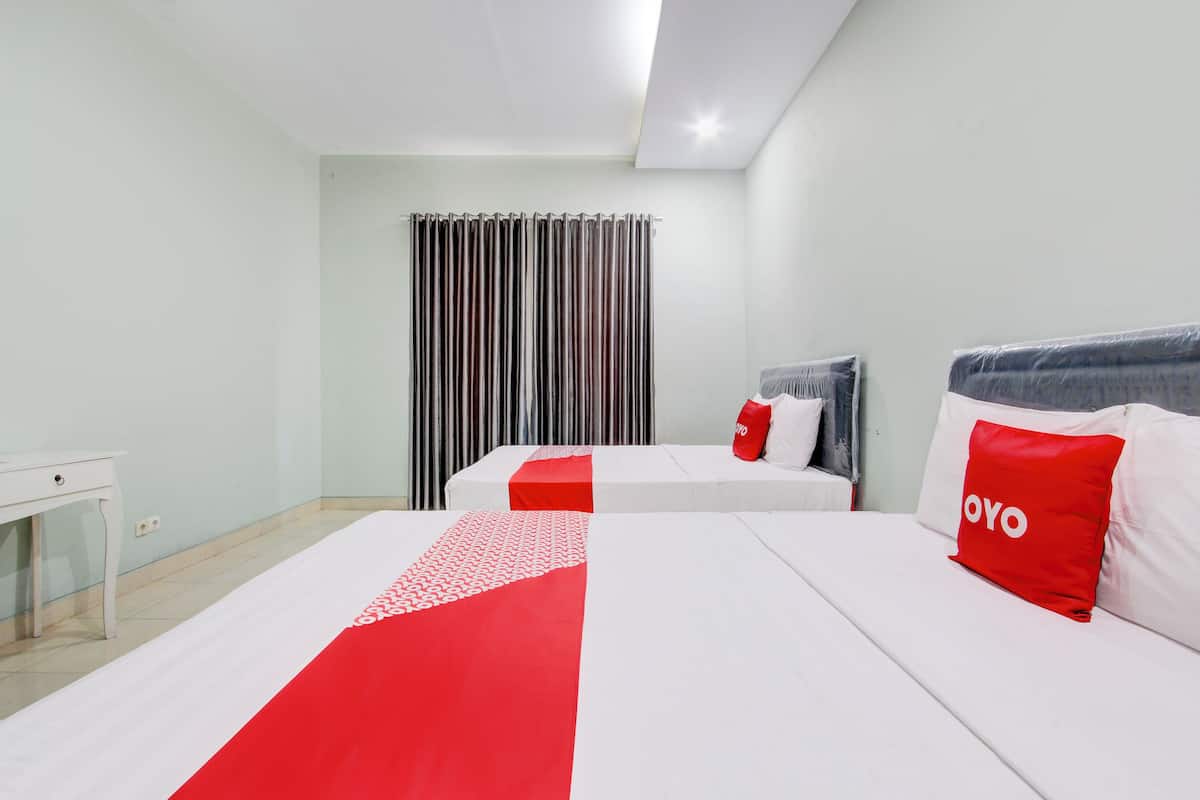 Habitación de hotel con dos camas, un escritorio y una ventana con cortinas.
