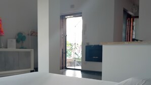 Een slaapkamer met een groot bed, een witte kledingkast, een bureau met een computer en uitzicht op het buiten via een deur.