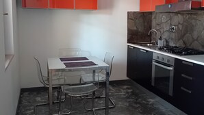 Een kleine keuken met een eettafel, stoelen en een fornuis.