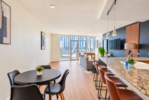Cocina moderna con barra, comedor y amplios ventanales con vistas a la ciudad.