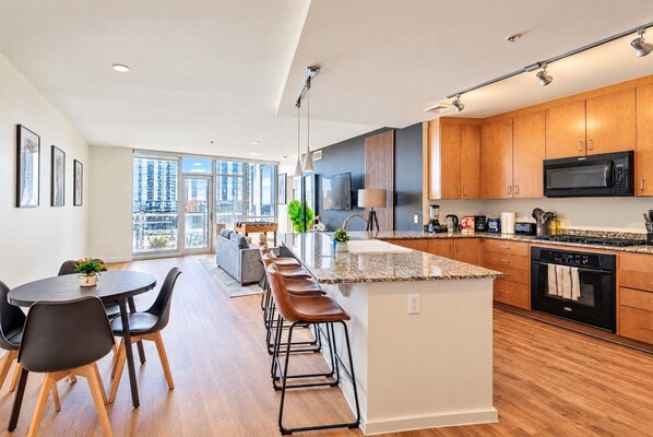 Una cocina moderna con armarios de madera, una isla central y un comedor con mesa y sillas.