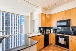Una cocina moderna con armarios de madera, un microondas negro y una campana extractora de acero inoxidable.
