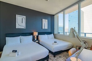 A hotel room with two beds, a nightstand with a lamp, and artwork on the wall.