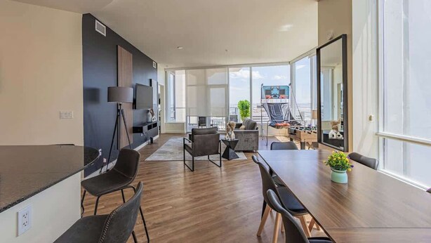 A modern living room with a dining area, large windows, and a view of the city.