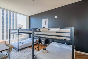 Et moderne hotelværelse med køjesenge, et lille skrivebord og udsigt over byen.