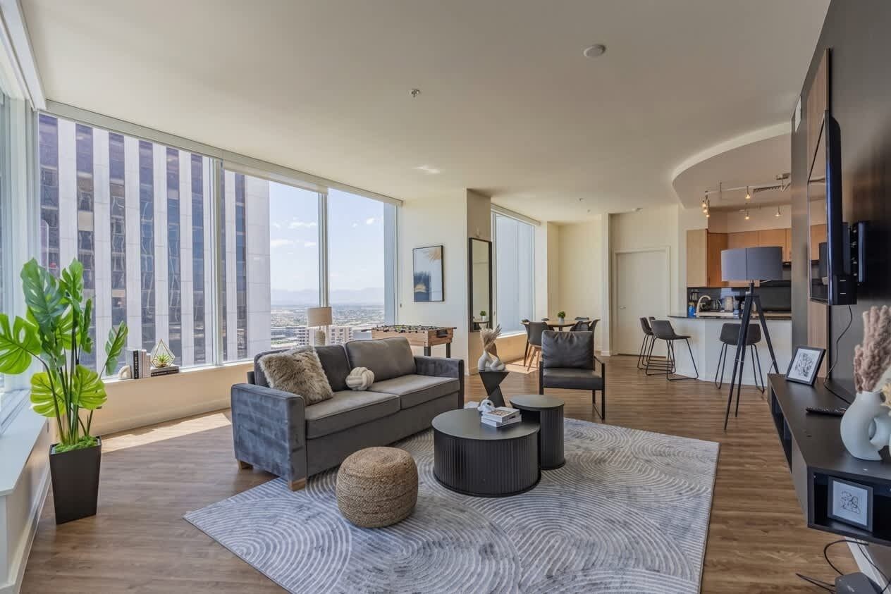 A modern living room with a sofa, coffee table, and a view of the city.