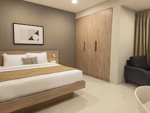 A modern bedroom with a bed, bedside table, and a wardrobe. - Olive Hotel Millers Road by Embassy Group (Bengaluru)