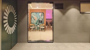A modern interior with a wooden ceiling, a glass door entrance, and a seating area with two chairs and a small table.