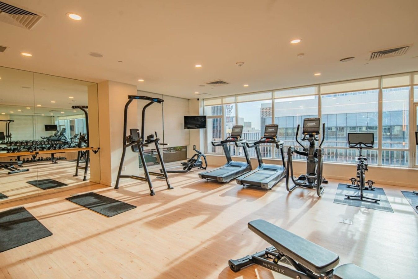 A gym with treadmills, elliptical machines, and a bench.