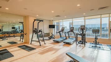 A gym with treadmills, elliptical machines, and a bench.