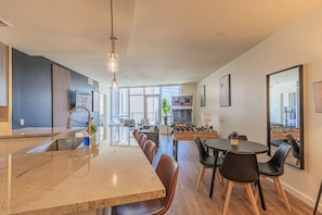 Una cocina moderna con encimera de mármol, un área de comedor con sillas y una mesa de futbolín.