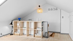 A modern, well-lit room with a sloped ceiling, a wooden bookshelf, and a hanging light fixture. - 2 bedroom amazing home in Svaneke (Svaneke)