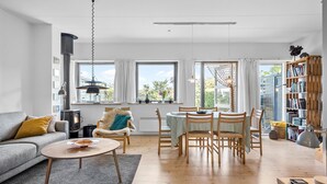 A modern living room with a sofa, a round dining table with chairs, a bookshelf, and a fireplace. - 2 bedroom amazing home in Svaneke (Svaneke)