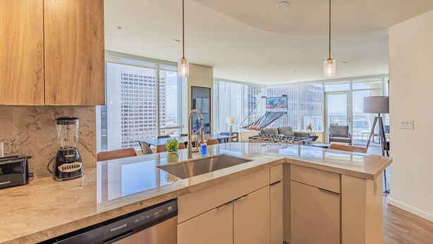 A modern kitchen with a central island, built-in appliances, and large windows offering city views. - DT PHX Stay | Pool, Gym, Balcony, W/D + Parking (Phoenix)