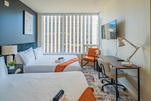 A hotel room with two beds, a desk, a chair, a TV, and a window with blinds. - Modern HighRise Sanctuary+Gym+Pool+Prking+W/D (Phoenix)