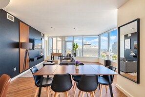 Une chambre d’hôtel moderne dotée d’une grande table à manger, de sièges confortables, d’un baby-foot et offrant une vue sur la ville.