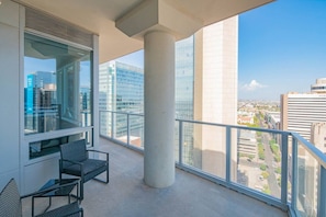 Un balcon donnant sur un paysage urbain, une chaise et un grand pilier.