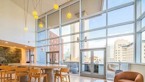 A modern interior with a large window, a central table with chairs, and a sofa. - Stadium District Apt Pool,Gym,Balcony,Parking,WD (Phoenix)