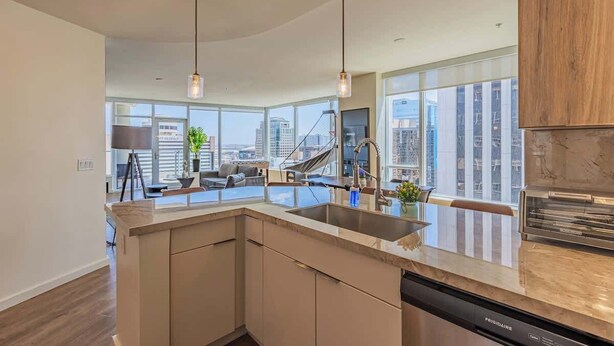 A modern kitchen with a large island, stainless steel appliances, and a view of the cityscape. - Stadium District Apt Pool,Gym,Balcony,Parking,WD (Phoenix)