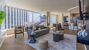 A spacious living area with a sofa, coffee table, and a foosball table. There is a staircase leading to an upper level, and a kitchen area is visible in the background. - Stadium District Apt Pool,Gym,Balcony,Parking,WD (Phoenix)