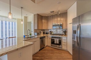 A modern kitchen with a central island, stainless steel appliances, and wooden cabinetry. - Stadium District Apt Pool,Gym,Balcony,Parking,WD (Phoenix)