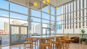 Un interior moderno con un amplio muro de cristal, una mesa redonda con sillas y vistas a la ciudad.