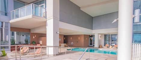A hotel pool area with a small pool, lounge chairs, and a seating area.