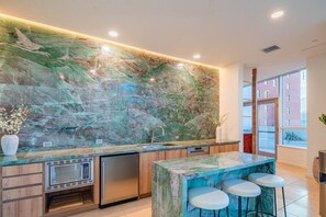 A modern kitchen with a marble backsplash, built-in appliances, and a bar area with stools.