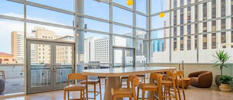 A modern interior with a large glass window, a round table with chairs, and a potted plant.