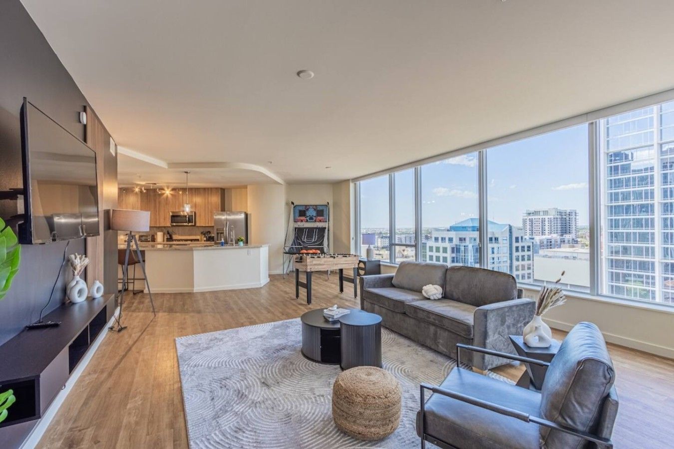 Un apartament modern amb saló, cuina i grans finestres que donen vista a la ciutat.