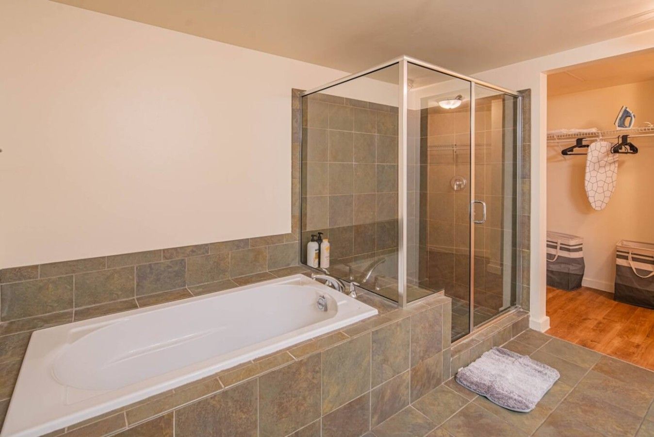A bathroom with a glass-enclosed shower, a bathtub, and a tiled floor.