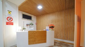 A reception desk with a wooden panel, a television above it, and a sign indicating no smoking. - Hotel Rivabella (Davoli)