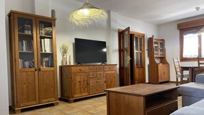 A living room with wooden furniture, a TV, and a large window. - Casa Rural LA Divisa Hay Lugares Donde uno se Queda y Lugares que Quedan en uno (Boceguillas)
