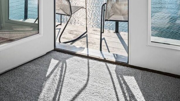 Een balkon met uitzicht op zee, twee stoelen en een glazen deur.