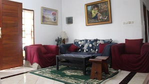 Una sala de estar con un sofá, dos sillones rojos, una mesa de centro y un tapete estampado.