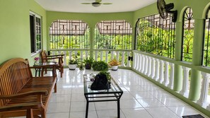A sunlit room with a balcony, wooden furniture, and potted plants. - Montego Bay 3-bed Home, Sleeps 6 Parking & Garden (Montego Bay)