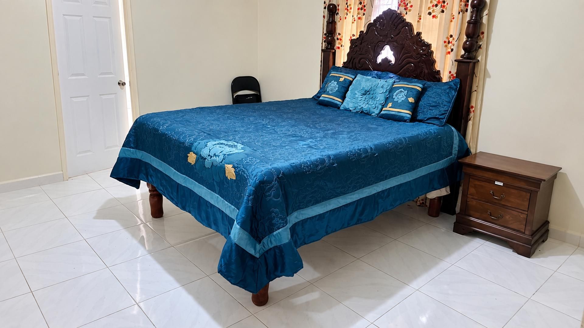 A bedroom with a bed, a nightstand, and a door.