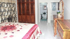 A bedroom with a large bed, wooden wardrobe, and a dresser. - Sun Valley Retreat in Montego Bay (Montego Bay)